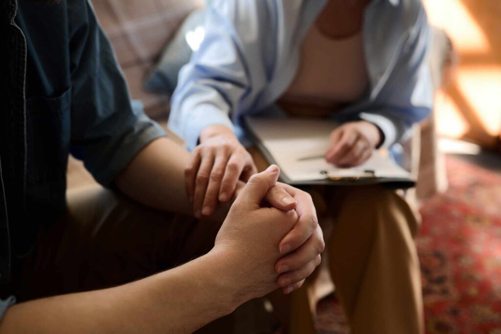 Close-up of psychologist supporting her patient holding his hand during session in office